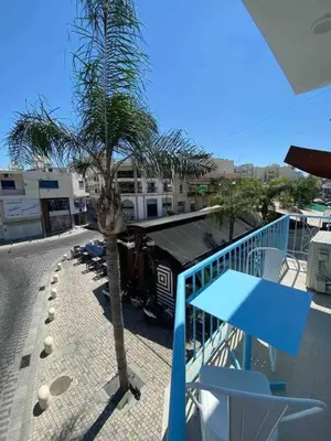 a palm tree on a balcony with a blue table and chairs at 2 bedroom apt in Ermou 4 minute walk beach in Larnaka