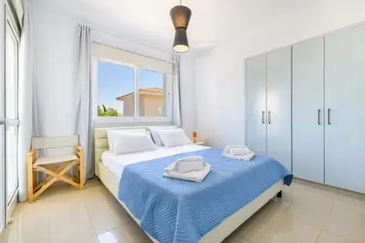 a white bedroom with a bed and a window at Villa Lela Serena by Ezoria Villas in Protaras