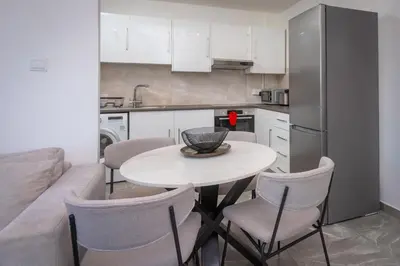 a kitchen with a table and chairs and a refrigerator at White Arches Apt #2 by TrulyCyprus in Limassol