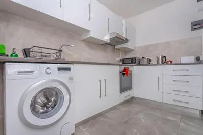 a kitchen with a washing machine in a white kitchen at White Arches Apt #2 by TrulyCyprus in Limassol