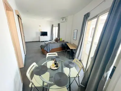 a living room with a table and chairs and a bed at High Speed Holiday Apartment in Larnaka
