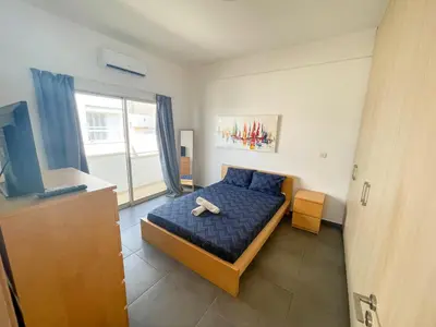 a bedroom with a blue bed and a television at High Speed Holiday Apartment in Larnaka