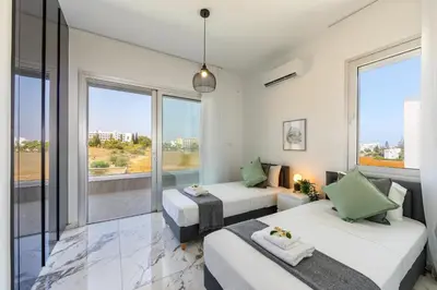 two beds in a room with large windows at Protaras Sol e Mar Villa 3 in Protaras