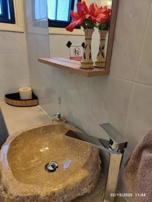 a bathroom with a sink with a vase of flowers at Palm garden paradise in Pervolia