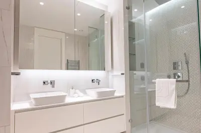 a white bathroom with two sinks and a shower at Del Mar Beachfront 'C' 2 Bedroom Residence in Limassol