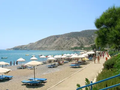 a beach with chairs and umbrellas and the ocean at Maria Villa in Pissouri
