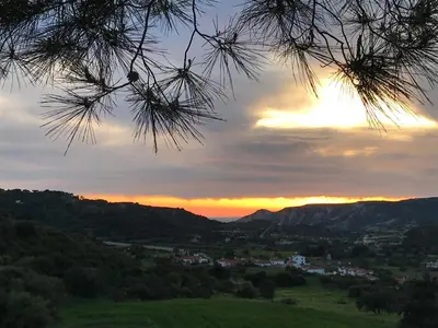 a sunset over a green field with a mountain at Maria Villa in Pissouri