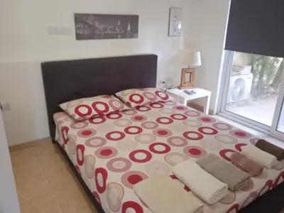 a bedroom with a bed with red and white sheets and a window at Nicosia rest and relax 1 bedroom apartment in Nicosia