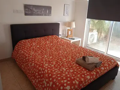 a bedroom with a bed with a orange bedspread and a window at Nicosia rest and relax 1 bedroom apartment in Nicosia