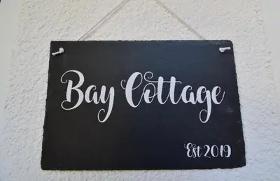 a chalkboard sign that says bay fisheries hanging on a wall at Bay Cottage Beautiful cosy luxury cottage - Beach area in Pissouri