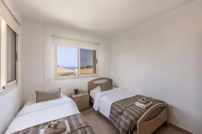 two beds in a small room with a window at Pelagos apartment 6 in Paralimni