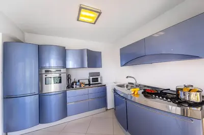 a large kitchen with blue cabinets and appliances at Protaras Pallini 201 Seaside Suite in Protaras