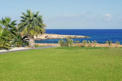a park with palm trees and a view of the ocean at VERONICA - Coralli Beachfront Apartment in Protaras