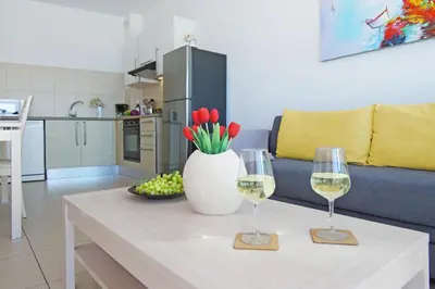 a table with two wine glasses and a vase with flowers at VERONICA - Coralli Beachfront Apartment in Protaras