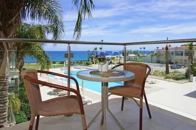 a table and chairs on a balcony with a view of the ocean at Niovi - Coralli Beachfront Apartment in Protaras