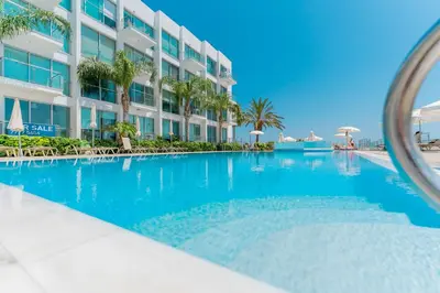 a swimming pool in front of a building at SHARON - Coralli Beachfront Apartment in Protaras