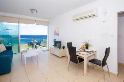 a living room with a couch and a table with chairs at GABRIELA - Coralli Beachfront Apartment in Protaras