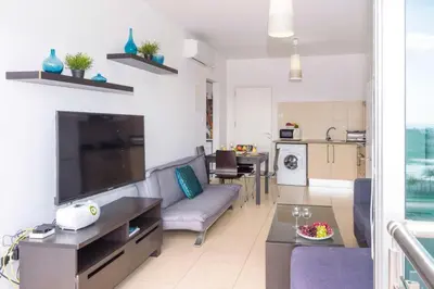 a living room with a couch and a tv and a kitchen at LAILA - Coralli Beachfront Apartment in Protaras