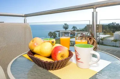 a basket of fruit on a table with a cup and juice at LAILA - Coralli Beachfront Apartment in Protaras