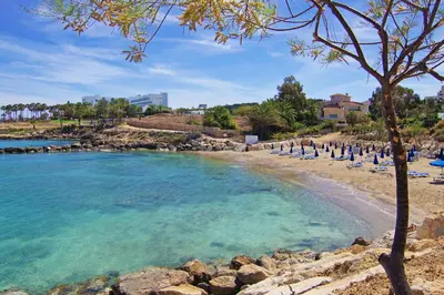 a beach with a bunch of chairs and the water at BLISS - Coralli Beachfront Apartment in Protaras
