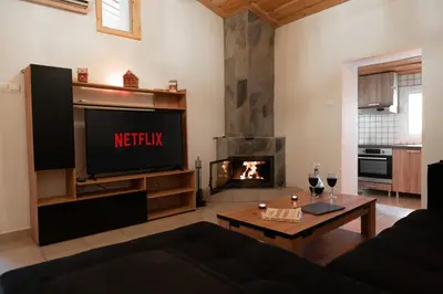 a living room with a television and a fireplace at Aprosmeno Jacuzzi House 4 in Agros