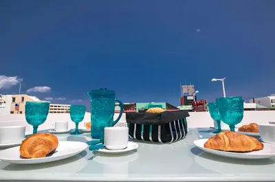 a table with plates of food and blue glasses at Evas Apartment in Protaras