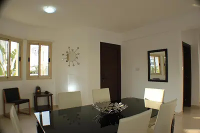 a dining room with a glass table and white chairs at Palm Tree Villas in Protaras