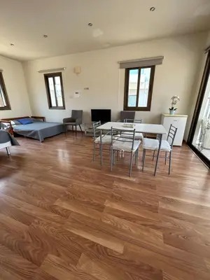 a living room with a wooden floor and a table and chairs at Extremely comfy apt with spacious private terrace 10min walk to the beach & in Town in Larnaka