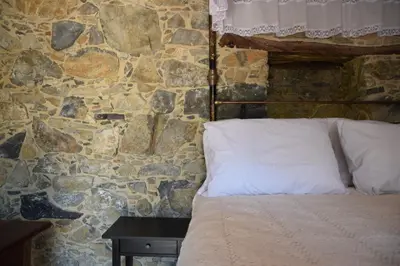 a bed in a room with a stone wall at Konatzin tou Massou by Raise in Moutoullas