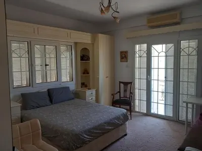 a bedroom with a bed and a chair and windows at Vasilis house in Mor Menekshe