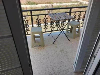 a porch with a table and two chairs on a balcony at Vasilis house in Mor Menekshe