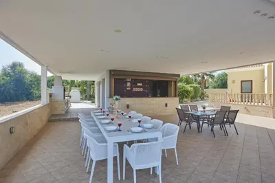a patio with white tables and chairs at Sparta Luxury Villa in Protaras