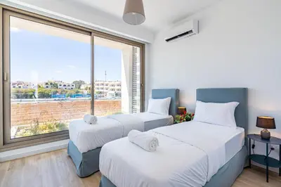 two beds in a room with a large window at Cyan 3-Bedroom Villa in Protaras in Paralimni