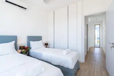 two beds in a room with white walls and wooden floors at Cyan 3-Bedroom Villa in Protaras in Paralimni