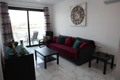 a living room with a red couch and a table at Όμορφο καινούργιο διαμέρισμα σε μικρή πολυκατοικία in Voroklini
