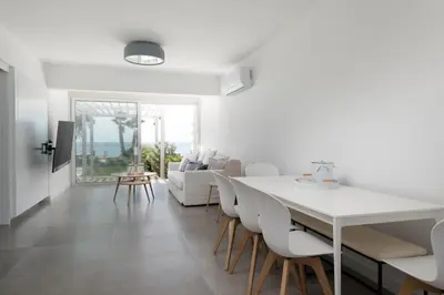 a white dining room with a white table and chairs at The MedView Garden House in Pervolia