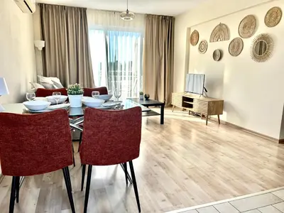 a living room with a table and chairs and a television at Nissi 3 C14 Sea View Top Floor Apartment in Ayia Napa