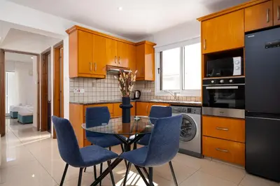 a kitchen with a glass table and blue chairs at The Saline Views Makenzy in Larnaka
