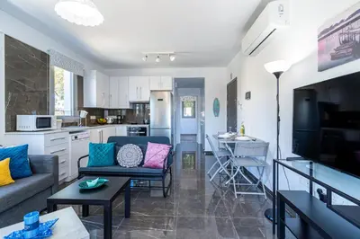 a living room with a couch and a kitchen at Kmeidos 1-Bedroom Apartment in Larnaca in Larnaka