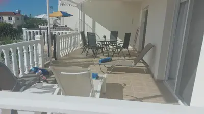 a balcony with chairs and tables and an umbrella at Nissi Golden Sands Sunny Apartment A1D4 in Ayia Napa