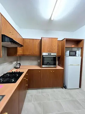 a kitchen with wooden cabinets and a white refrigerator at Joanna Court rooms in Larnaka