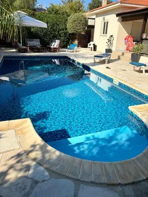a swimming pool with blue water in a backyard at LE CAROUBIER splendid 3 bedrooms bungalow in Zanaja