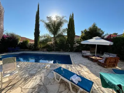 a swimming pool with chairs and an umbrella at LE CAROUBIER splendid 3 bedrooms bungalow in Zanaja