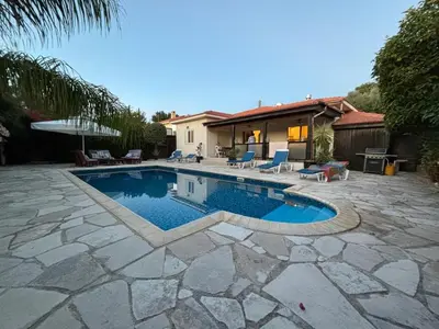 a swimming pool with a patio and a house at LE CAROUBIER splendid 3 bedrooms bungalow in Zanaja