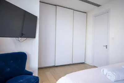 a bedroom with a tv and a blue chair at 360 Nicosia - 1 bedroom Luxurious Residence in Nicosia