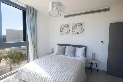 a white bedroom with a bed and a large window at Almaria Villas in Protaras
