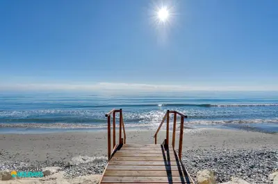 a wooden boardwalk leading to the beach with the ocean at Beachfront Villa Carpe Diem in Mor Menekshe