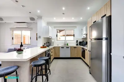 a kitchen with wooden cabinets and a stainless steel refrigerator at Beachfront Villa Carpe Diem in Mor Menekshe