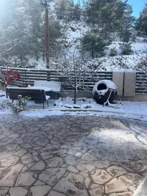 a snow covered park with a bench and a tree at DIAMOND Stone Wooden Guest House in Khandria