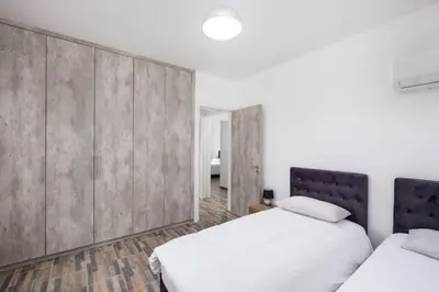 two beds in a white room with concrete walls at Happy Stay Apartment - Halefka Court in Larnaka
